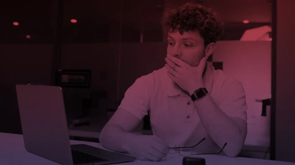 A business professional thinking in front of a computer, analyzing tech challenges.